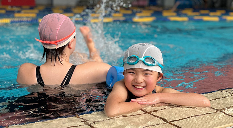 女の子が笑顔でプールに浮かんでいる