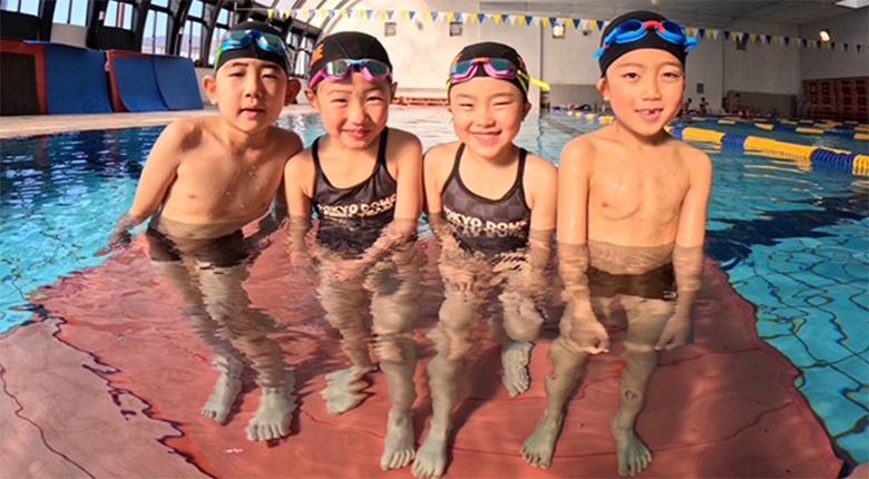 子ども達が水着でプールの水中に立っている